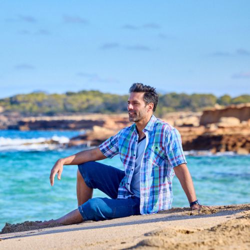 ein mann tragt ein karohemd und liegt am strand